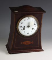 An Edwardian mahogany mantel clock, of waisted form, the 14cm white enameled dial applied with Roman