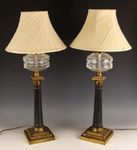 A pair of Victorian brass column oil lamps, later converted, each with a glass reservoir upon a