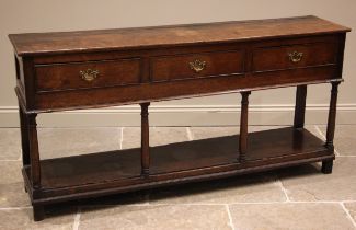 A George III oak dresser base, the plank top over three cock beaded and pine lined frieze drawers,