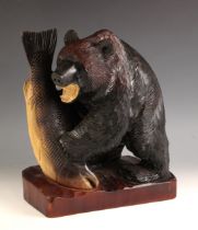 A Japanese carved wood model of a bear, 20th century, modelled with a fish in its paws, standing