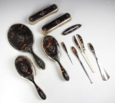 A George V silver and tortoiseshell mounted dressing table set, comprising two hair brushes, a