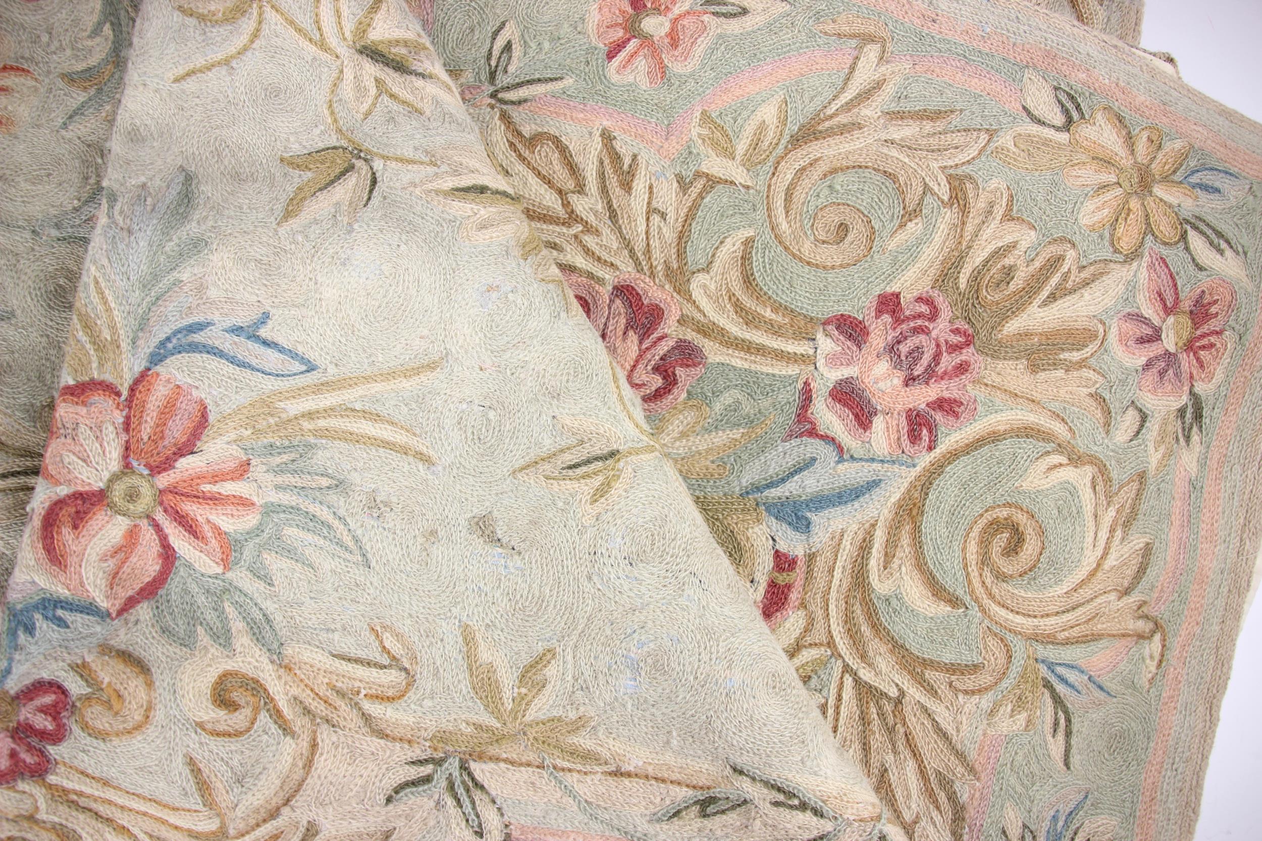 A crewelwork rug, with multi-coloured floral decoration to a pale green ground (slight - Image 2 of 2