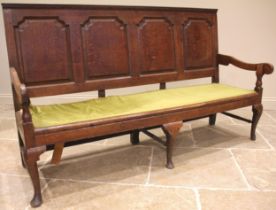 A George III oak panel back settle, four fielded panels and down swept arms upon baluster