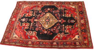 An Iranian village wool rug, in red, blue and ivory colourways, the central ogee medallion upon a