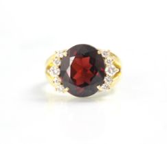 A garnet and diamond dress ring, the oval cut garnet with five round cut diamonds to each side,