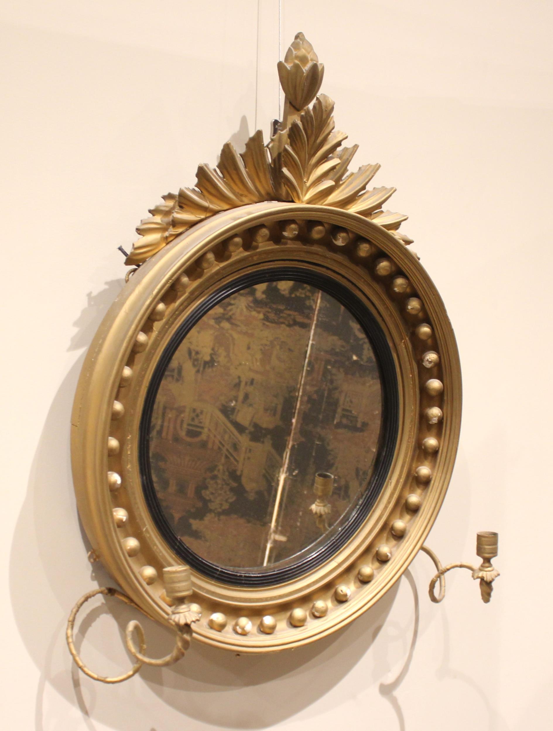 A Regency girandole wall mirror, with a leafy fruit crest over the moulded circular frame applied