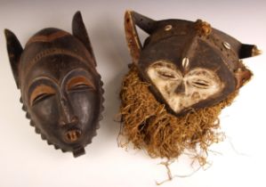 An African tribal double sided mask, 20th century, the white painted finish inset with cowrie shells