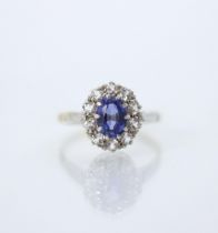 An Edwardian style synthetic sapphire cluster ring, the oval cut blue stone within surround of ten