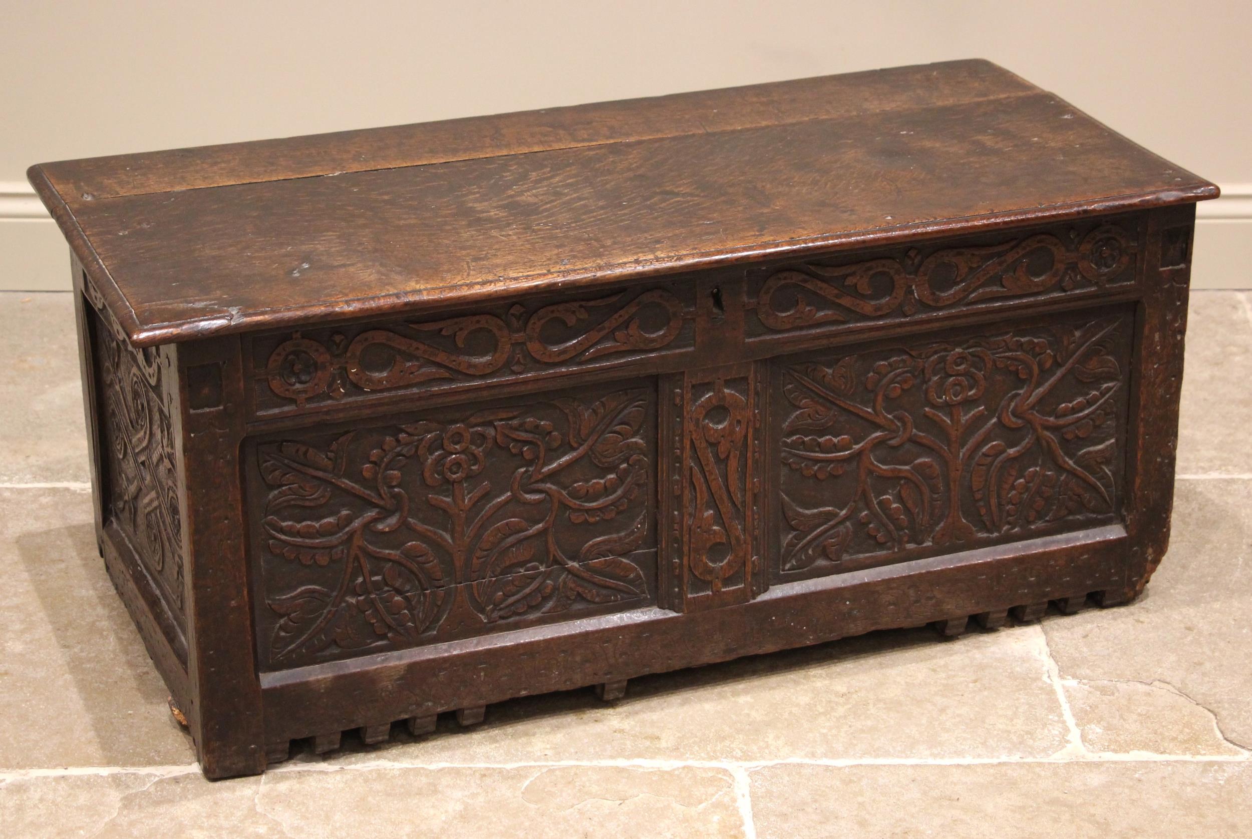 A late 17th century carved oak coffer, the hinged and moulded top over a carved frieze and twin