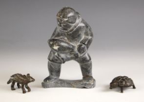 An Inuit soapstone carving modelled as a figure carrying a baby seal, indistinctly signed to base (