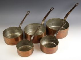 A graduated set of five copper saucepans, of typical form, the steel handles with pierced hanging