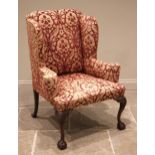 A George III style wing back armchair, mid 20th century, of country house proportions, in embossed