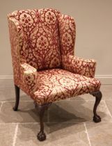 A George III style wing back armchair, mid 20th century, of country house proportions, in embossed