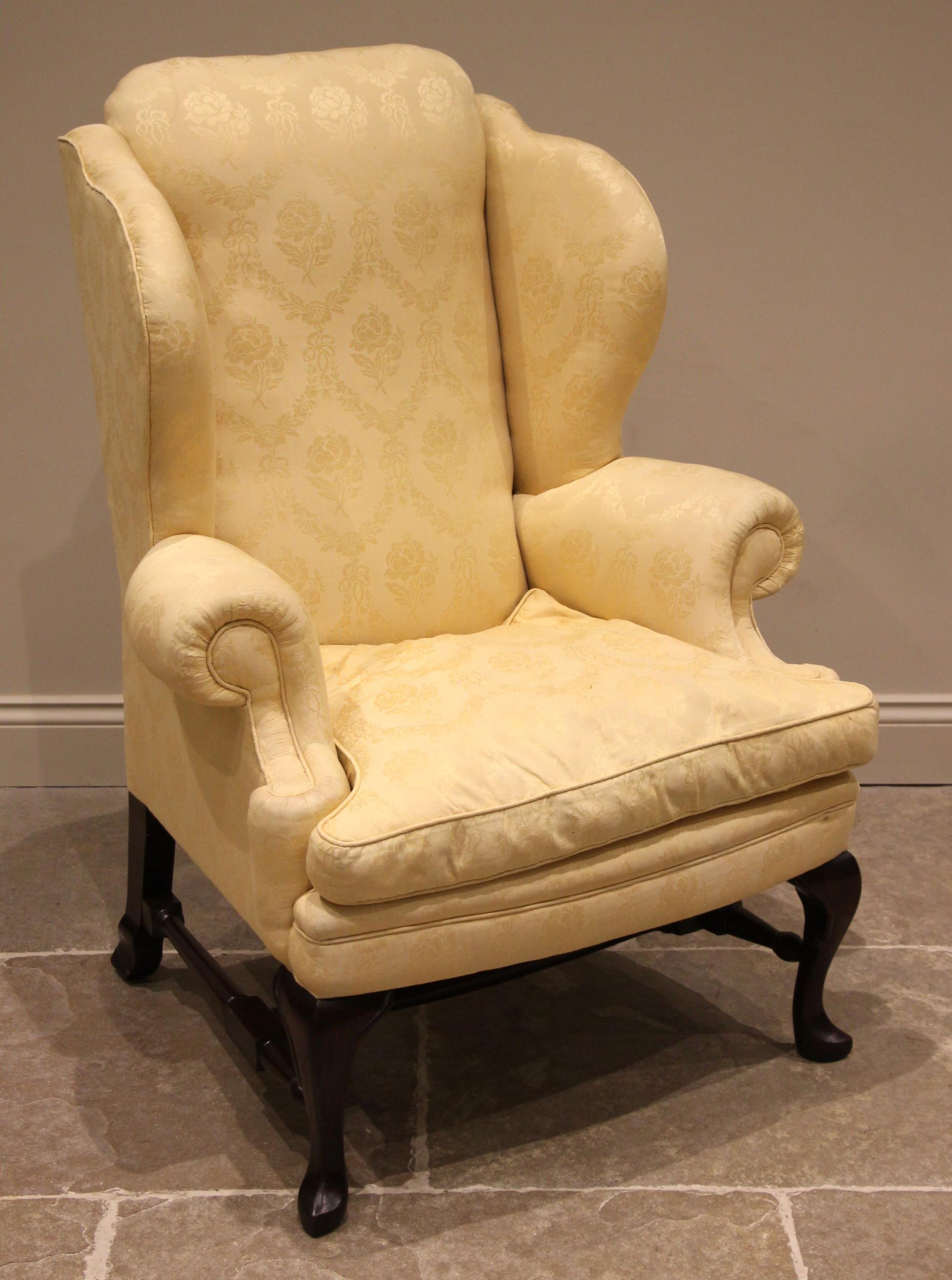 A George II style mahogany wingback armchair, late 20th century, in yellow damask foliate fabric,