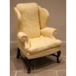 A George II style mahogany wingback armchair, late 20th century, in yellow damask foliate fabric,