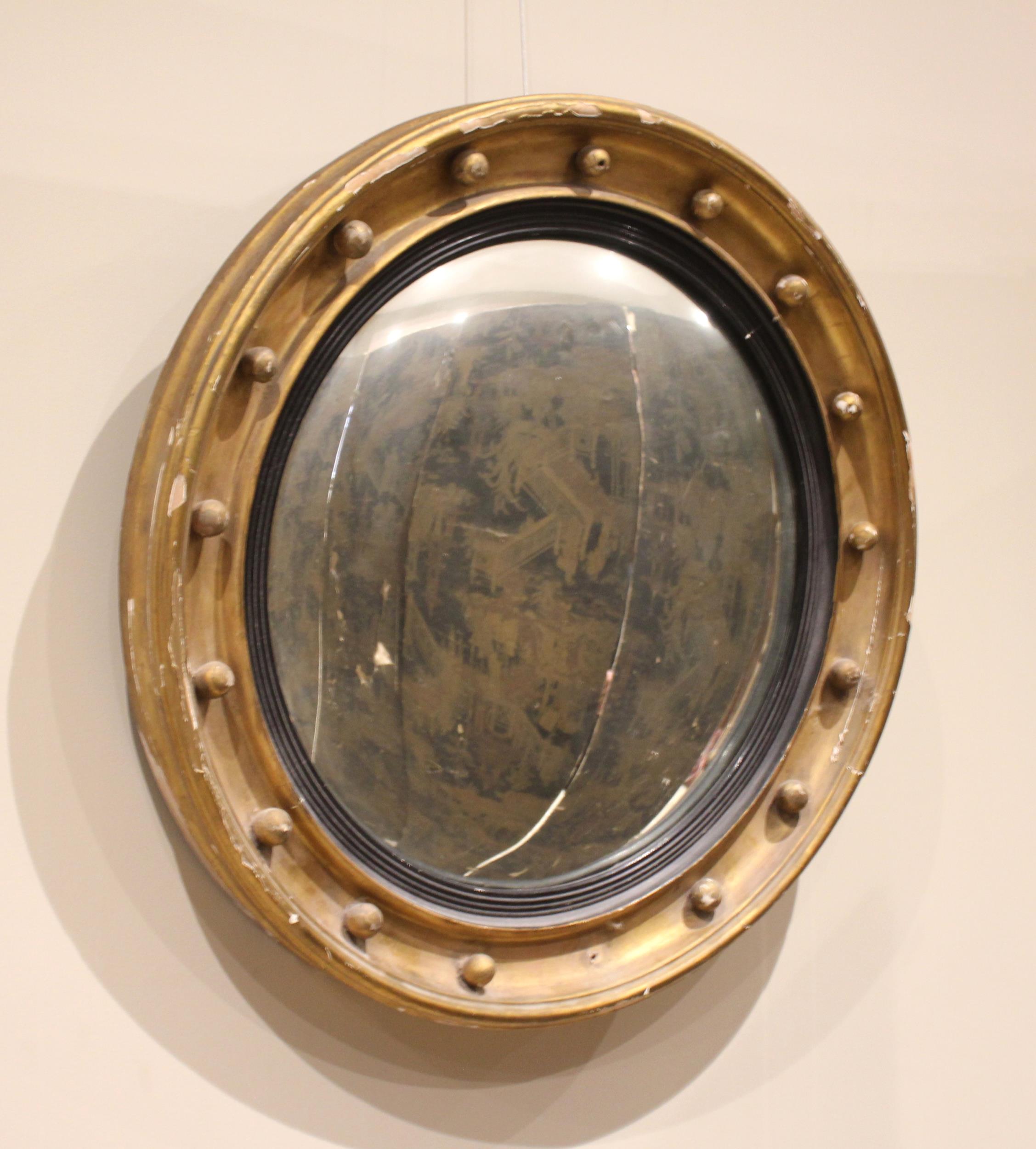 A Regency giltwood and gesso circular convex wall mirror, the circular moulded frame applied with
