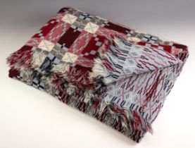 A Welsh blanket of traditional reversible geometric design in red, black and light blue, tassels