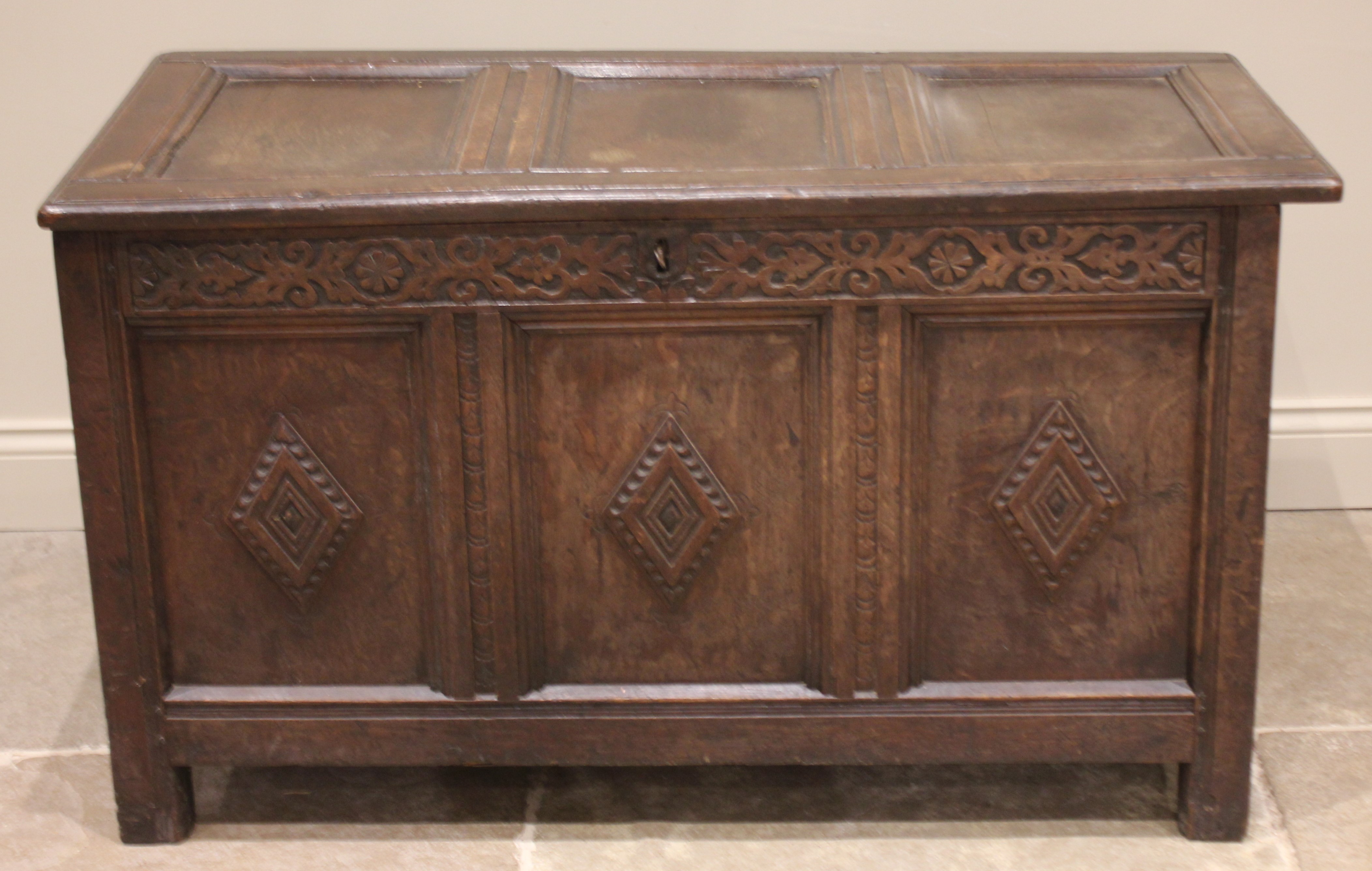 A late 17th/early 18th century oak coffer, the hinged cover over a carved frieze and three panels - Image 2 of 2