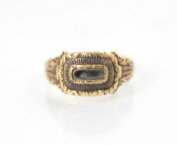 A 19th century style yellow metal mourning ring, the central vacant locket within carved mount and