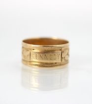 A 20th century yellow metal ring, the band ring with applied plaque engraved 'Kennedy' with leafy