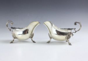 A near pair of George VI silver sauce boats, Walker and Hall, Sheffield 1938-1940, the shaped rim