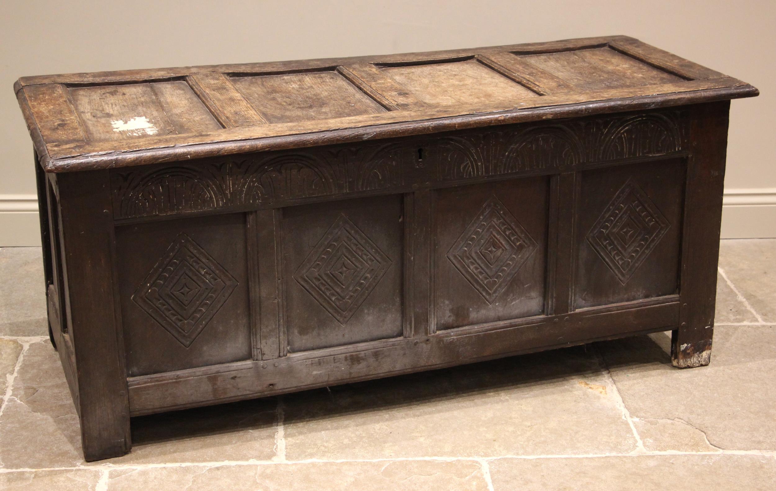 A late 17th/early 18th century oak coffer, the hinged four panel top over a lunette carved frieze