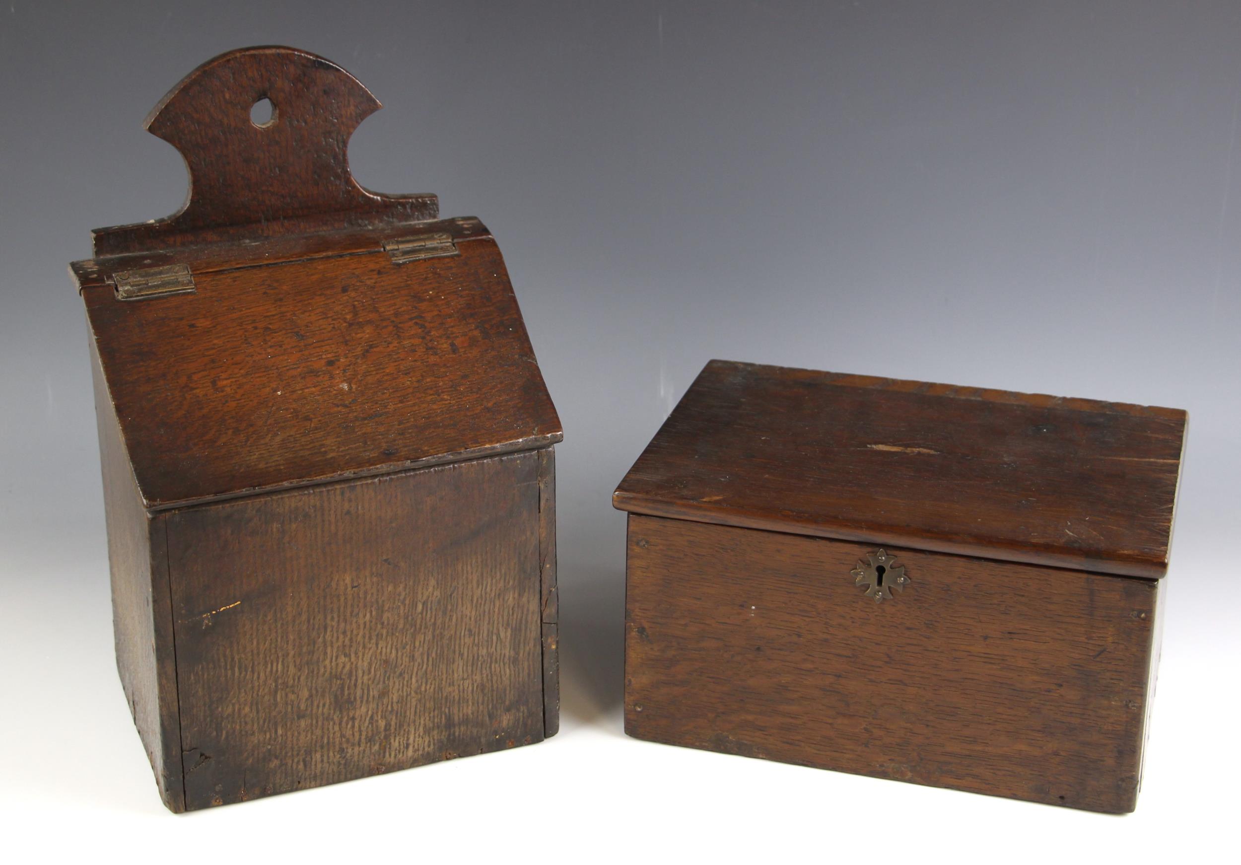 An 18th century oak candle box, the shaped back over a sloping hinged cover, later pine base, 36cm H