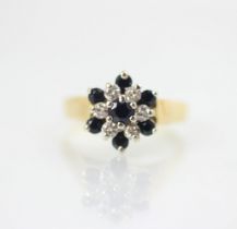 A 1970's 18ct yellow gold sapphire and diamond cluster ring, the central round cut sapphire within