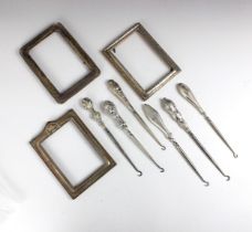 A group of six silver mounted button hooks, two with embossed cherub detailed examples, a plain
