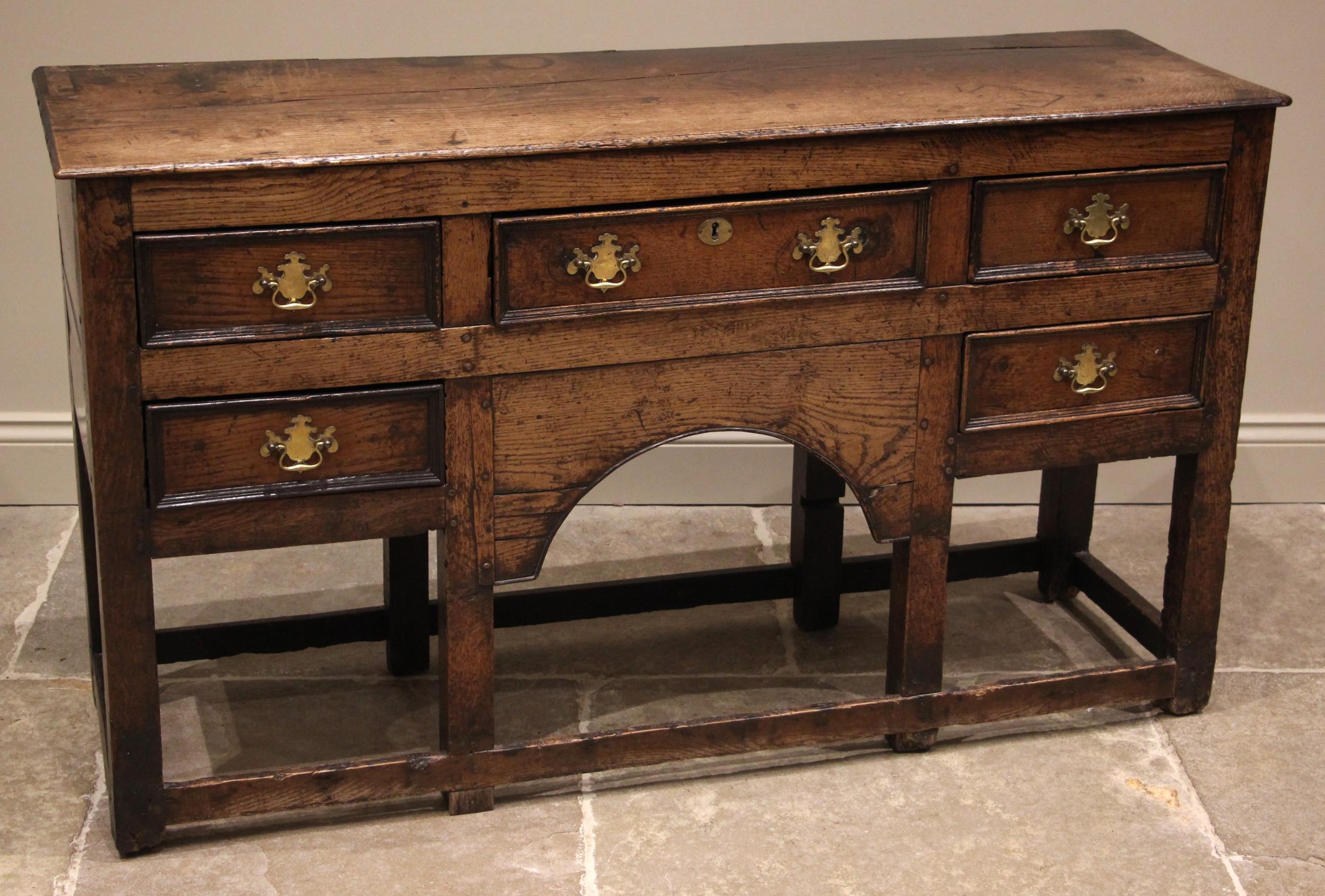 An 18th century oak dresser, the open plate rack with a moulded cornice and plain frieze over