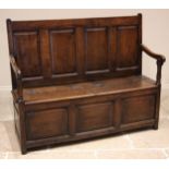 An 18th century Welsh oak box settle, of cottage proportions, the four panel back extending to the