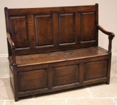 An 18th century Welsh oak box settle, of cottage proportions, the four panel back extending to the
