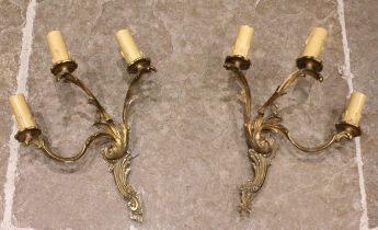 A pair of gilt metal Rococo three branch wall light fittings, of typical cast scroll foliate form,