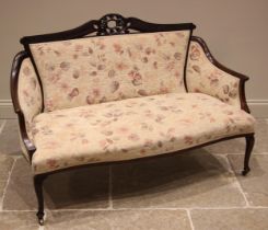 An Edwardian mahogany framed sofa, re-upholstered in floral fabric, the carved oval open work