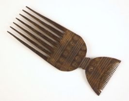 A tribal carved wooden comb, possibly Oceanic, one end with long prongs the other with finer