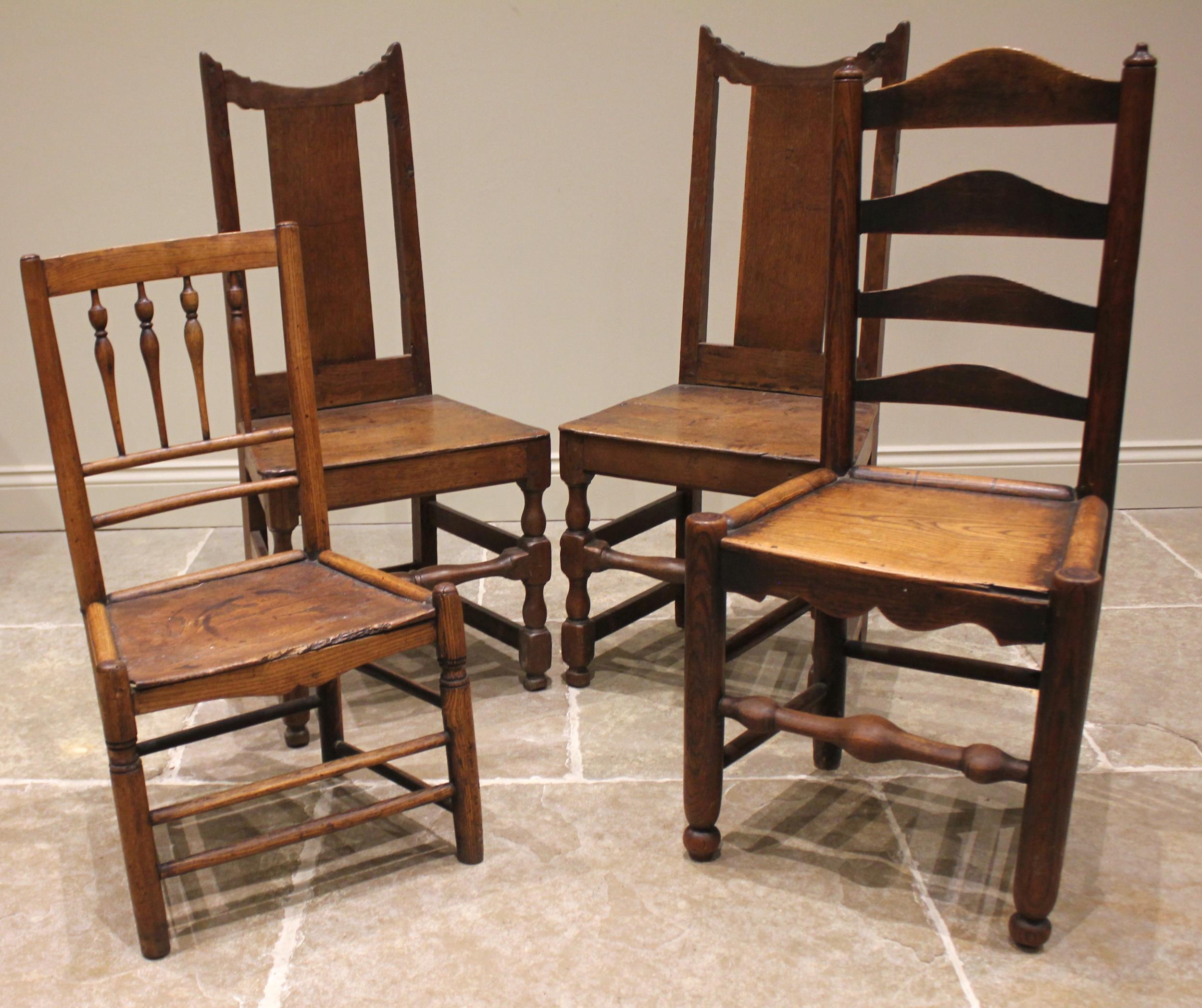 A pair of 18th century oak hall chairs, each with a splat back over a board seat upon baluster and