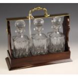 A mahogany finish three bottle tantalus, late 20th century, fitted with three matching square