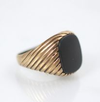 A yellow metal signet ring, the rectangular hardstone head within yellow metal engraved shoulders,