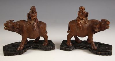 A pair of Chinese carved wood models of buffalo, 19th century, each modelled standing with a boy