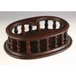 A 19th century mahogany twin decanter stand, of moulded oval form, the twin bottle aperture upon a