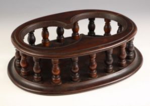 A 19th century mahogany twin decanter stand, of moulded oval form, the twin bottle aperture upon a