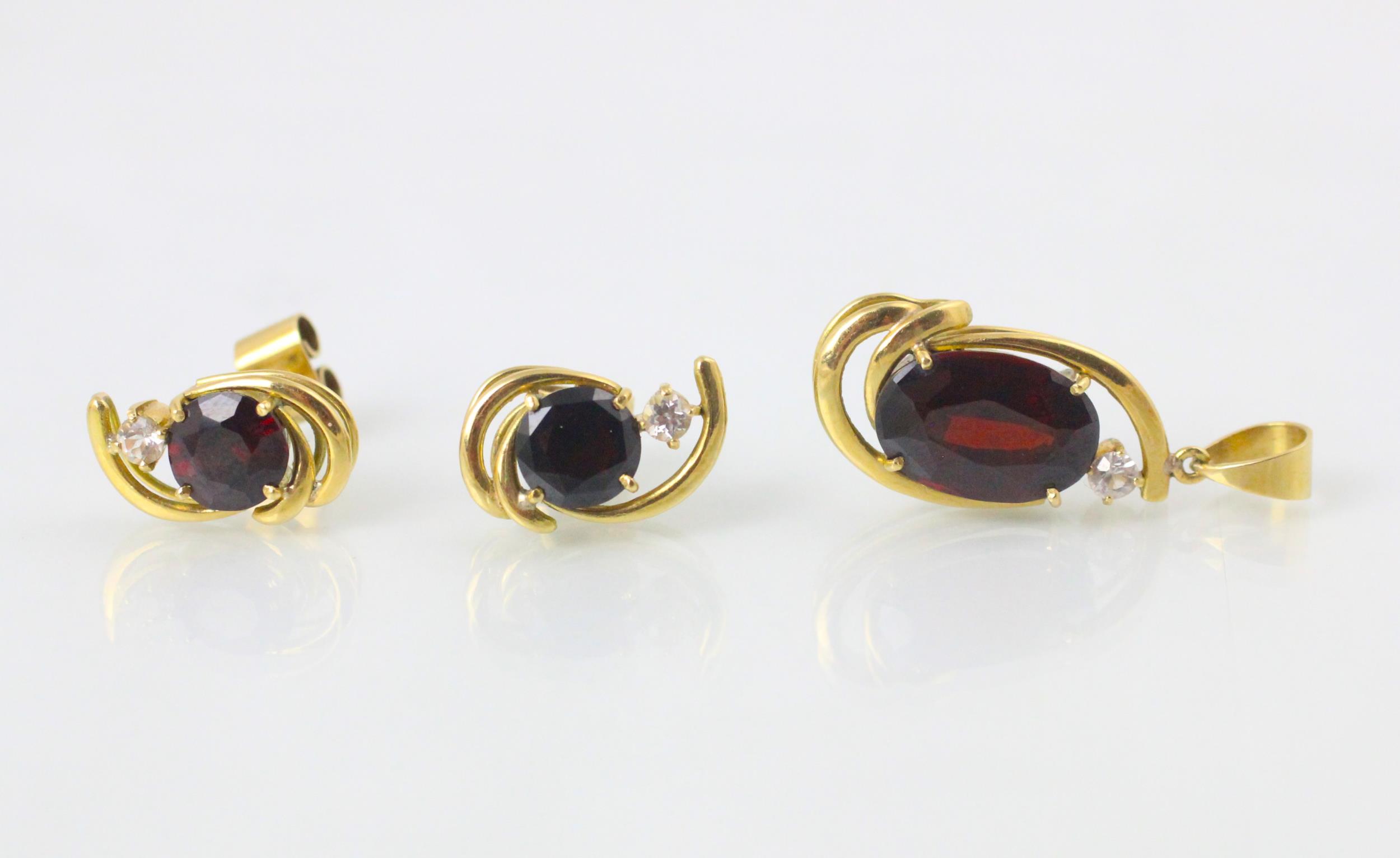 A suite of red stone jewellery, comprising ring, earrings, and pendant, the oval cut red stone set