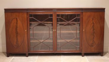 A 19th century inverted breakfront mahogany bookcase, the nulled frieze with a central oval crest