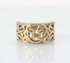 A yellow metal dress ring, the openwork sinuous design to the centre of the ring leading to white