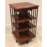 An Edwardian mahogany revolving bookcase, the square top inlaid with a central satinwood batwing