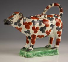 A pottery pearlware cow creamer, possibly Swansea Cambrian Ware, decorated with black and red