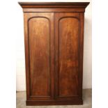 A Victorian mahogany double wardrobe, the cavetto cornice over a pair of arched panel doors