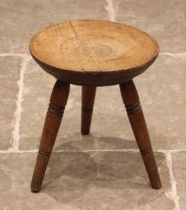 A provincial Welsh ash and sycamore tripod stool, the gently dished circular seat upon three