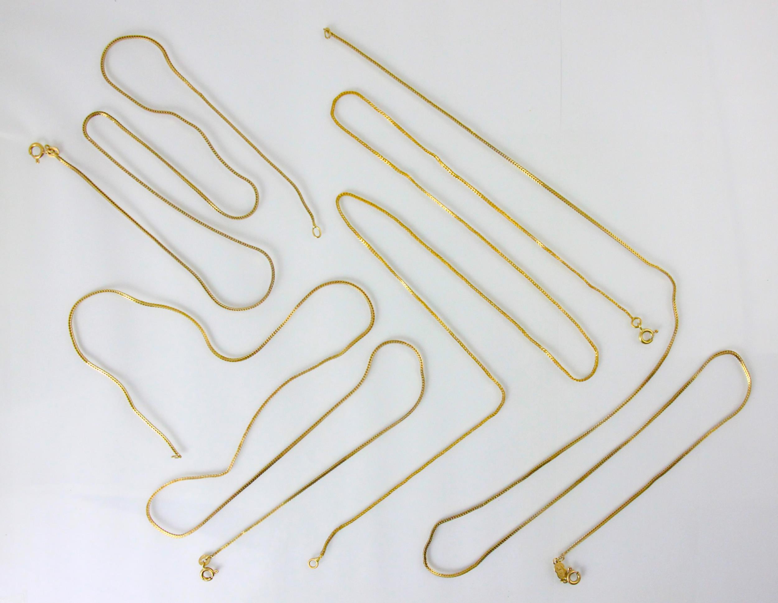 A group of four yellow metal chains, including a box link examples, a Uro-A-Erre example, all