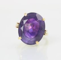 An untested amethyst set cocktail ring, the oval cut stone within yellow metal claw setting